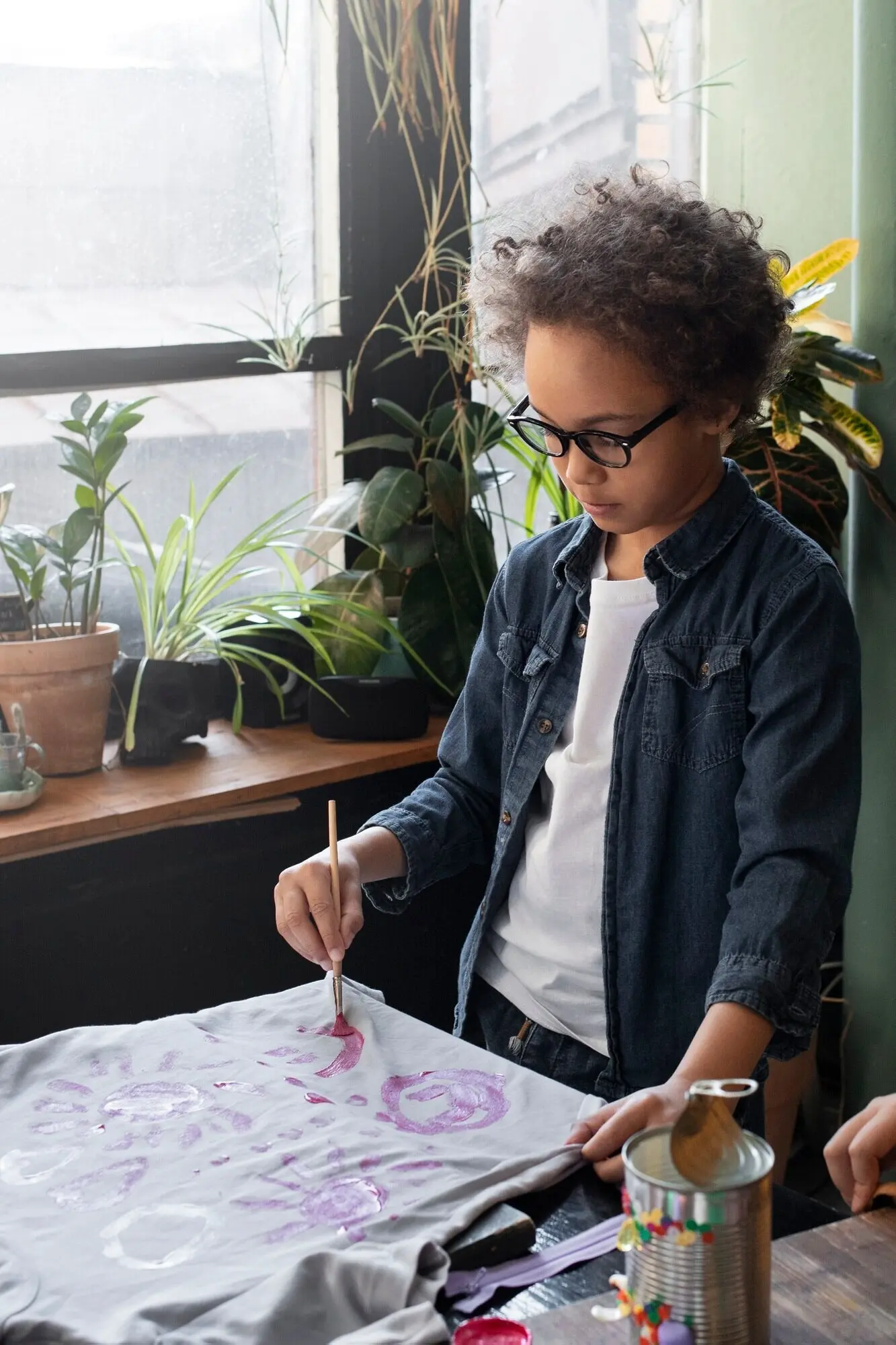 Ein junges Kind arbeitet an einem DIY-Bastelprojekt mit einem T-Shirt.